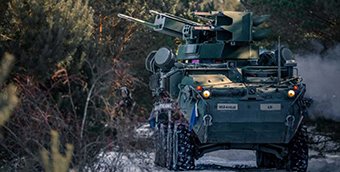 A Stryker vehicle with mounted M-SHORAD drives through a snowy path.